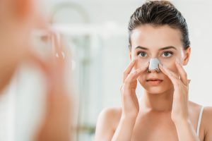 אישה עם תחבושת על האף מסתכלת במראה